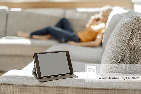 Tablette auf Couch mit entspannter Frau im Hintergrund
