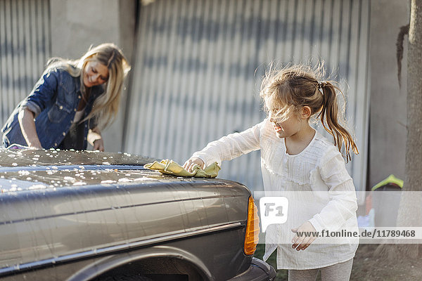 Mature woman and girl cleaning car together