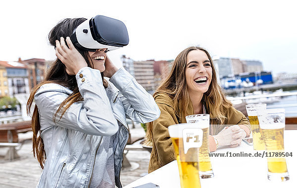 Two young women having fun with VR glasses in the city