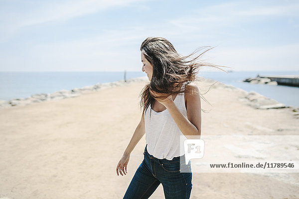Junge Frau am Strand stehend  Wind genießend