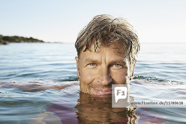 Porträt eines lächelnden Mannes beim Baden im Meer