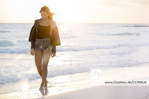 Junge Frau genießt den Strand bei Sonnenuntergang