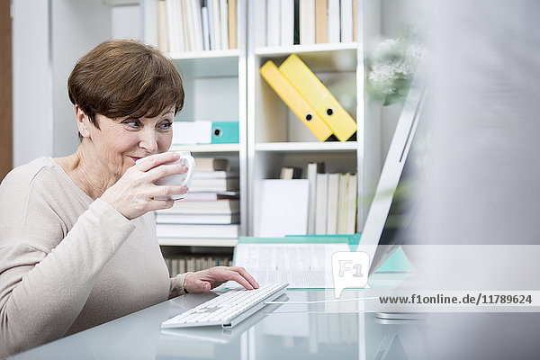Seniorin am Computer bei einer Tasse Kaffee