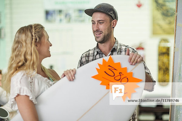 Shop assistant showing client surfboard prices