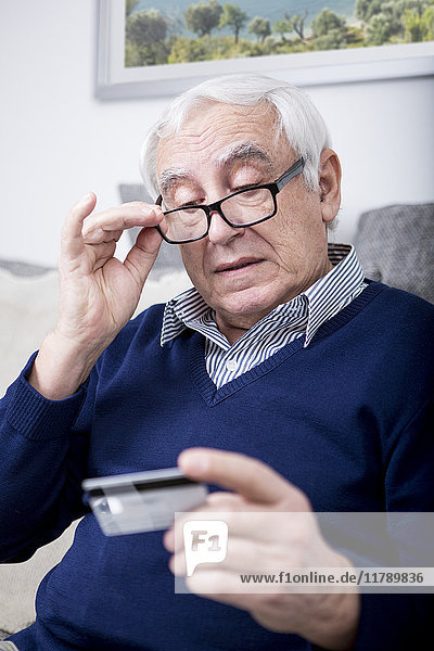 Älterer Mann  der seine Kreditkarte überprüft.