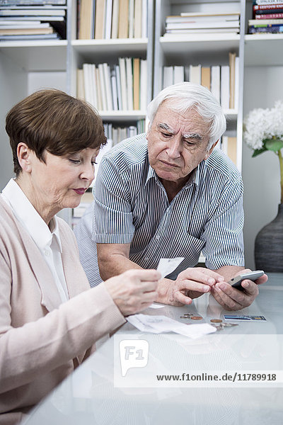 Senior couple with bills and calculator checking their expenses