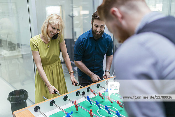 Colleagues playing foosball in office