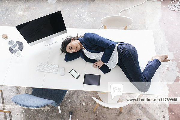 Geschäftsfrau schläft auf dem Schreibtisch im Büro