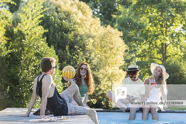 Vier Freunde entspannen sich am Poolrand