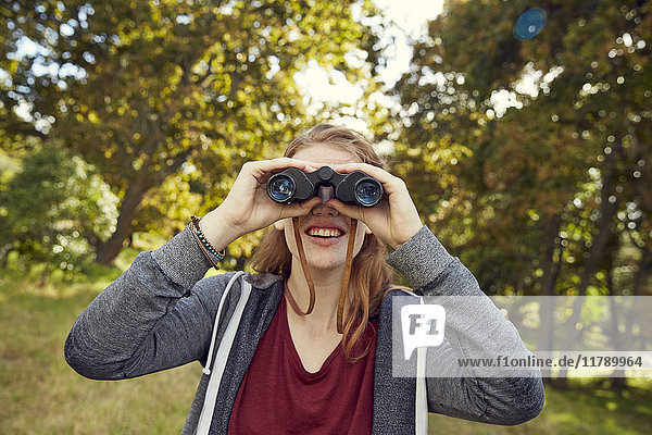 Smiling young woman using binoculars