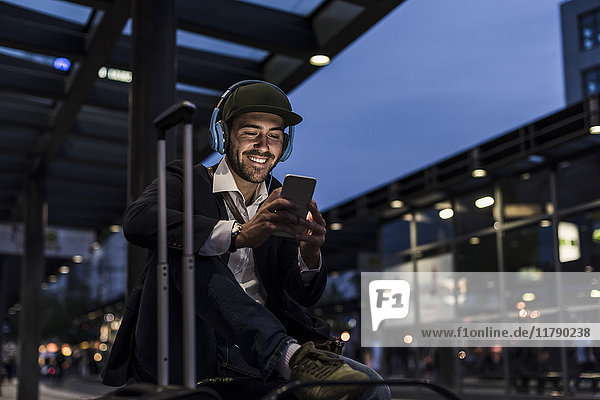 Young man in the city with headphones and cell phone in the evening