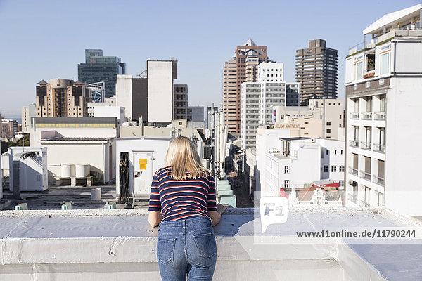 Young woman looking from a rooftop terrace  rear view