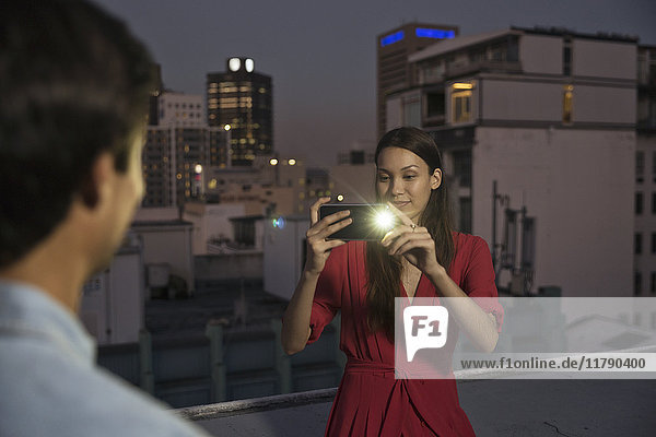 Young woman taking pictures of friends at a rooftop party