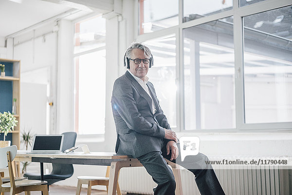Senior Geschäftsmann beim Musikhören mit Kopfhörern im Büro