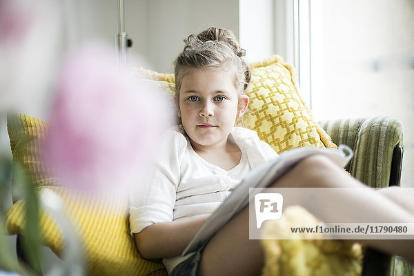 Porträt eines entspannten kleinen Mädchens mit Magazin auf Sessel
