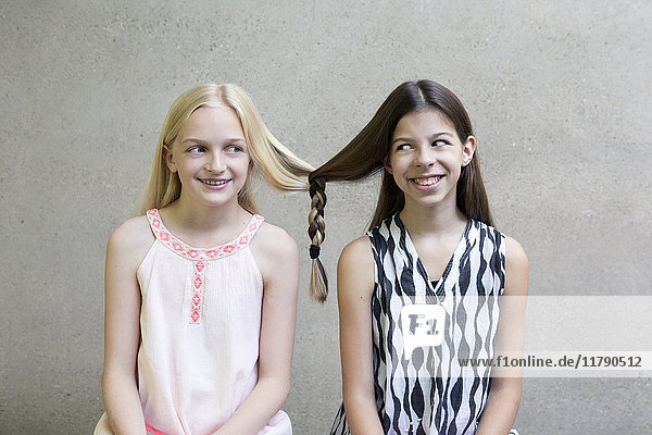 Portrait of two long-haired girls with one braid