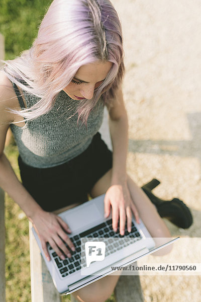 Junge Frau mit rosa grauen Haaren mit Laptop