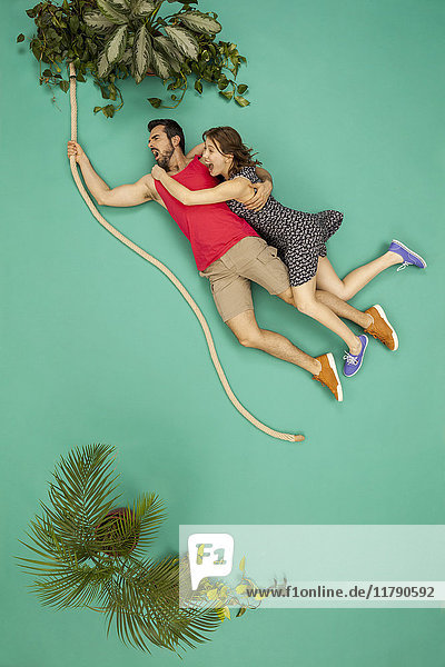 Couple swinging on a liana through the jungle