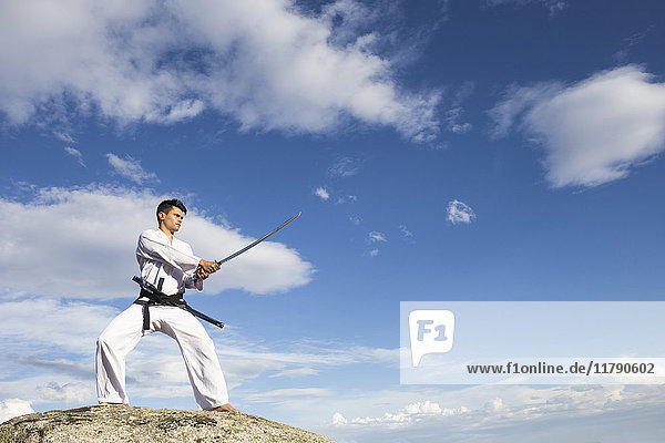 Man holding a katana sword on a rock