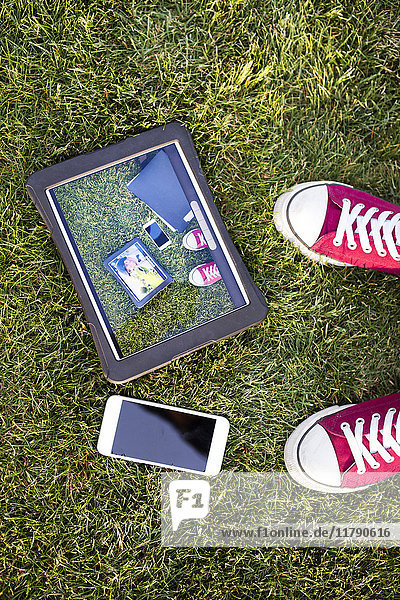 Smartphone  Tablett mit Fotografie und Füßen im Gras