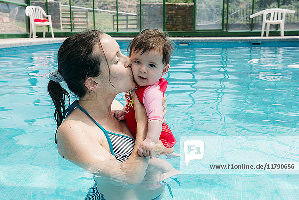 Mutter küsst ihr kleines Mädchen im Schwimmbad.