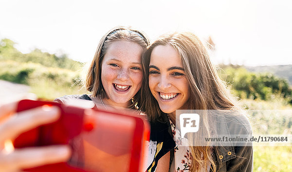 Zwei glückliche Mädchen  die mit einem Selfie nach draußen gehen.
