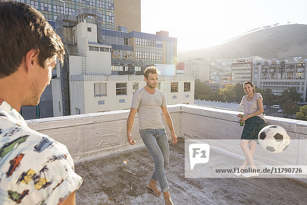 Friends meeting on rooftop terrace in summer  playing football