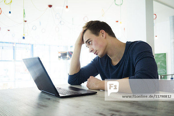 Junger Mann mit Laptop im Café