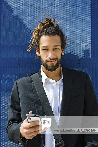 Portrait eines jungen Geschäftsmannes mit Dreadlocks per Smartphone