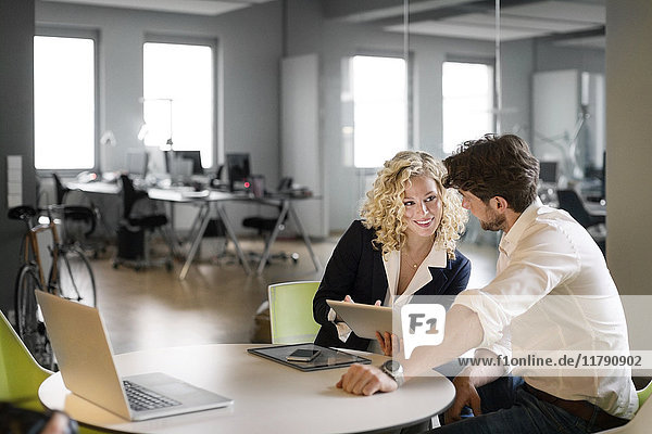 Businessman and woman discussing project in office  using digital tablet