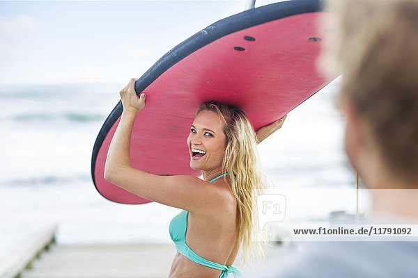 Happy woman carrying surfboard