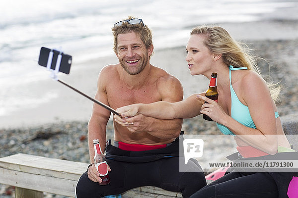 Ein Paar hat Spaß am Strand und nimmt sich einen Selfie.