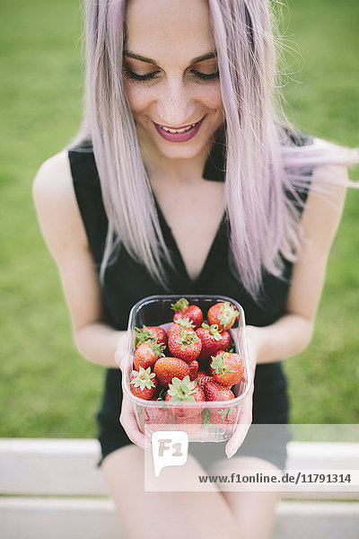 Lächelnde junge Frau mit einer Schachtel Erdbeeren
