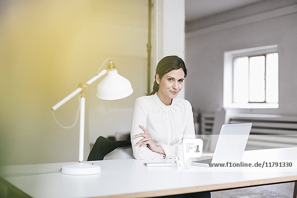 Portrait der Geschäftsfrau mit Laptop am Tisch