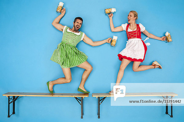 Man and woman at the Oktoberfest dancing on beer benches