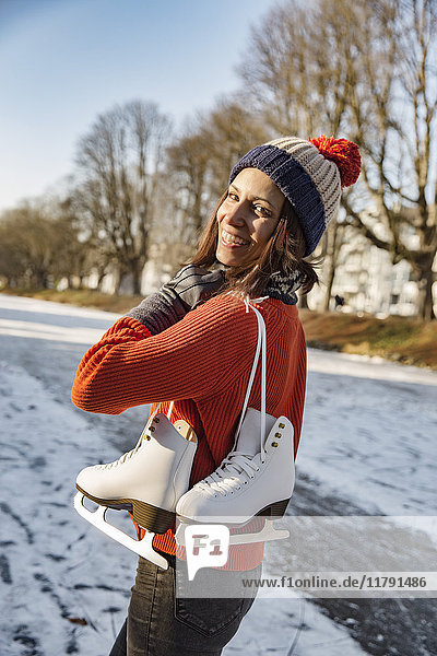 Happy woman on canal carrying ice skates