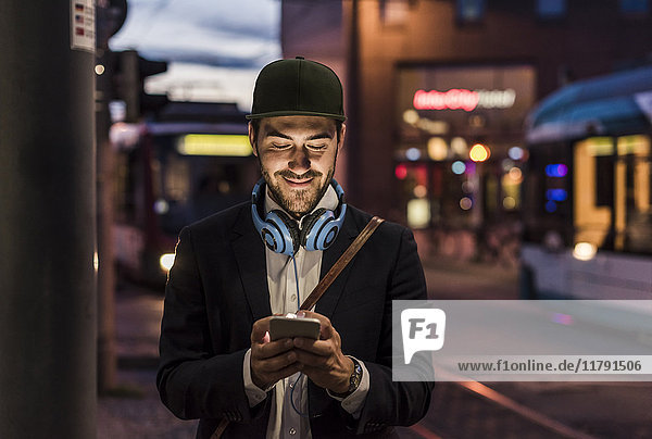 Young man in the city checking cell phone in the evening