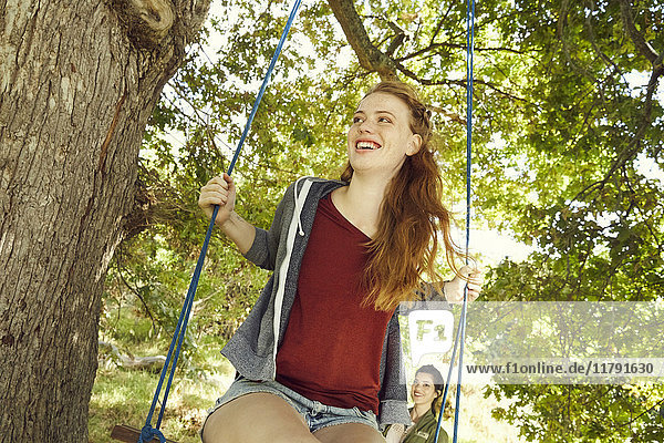 Portrait of smiling young woman sitting on a swing