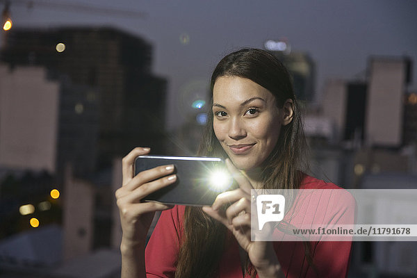 Young woman taking pictures of friends at a rooftop party