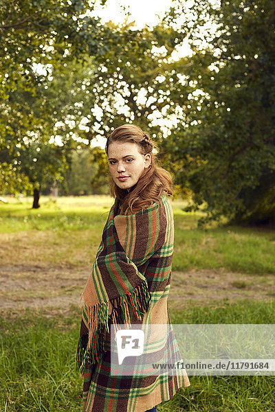 Portrait of young woman in nature wrapped in blanket
