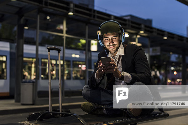 Young man in the city with headphones and cell phone in the evening