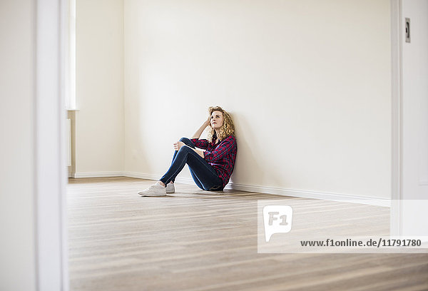 Young woman in new home sitting on floor