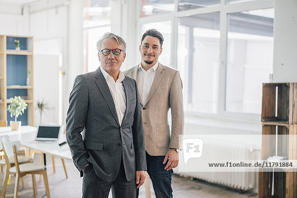 Portrait of confident old and young businessman in office