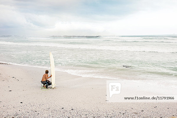 Mann am Strand mit Surfbrett