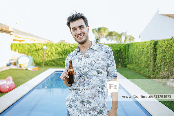 Junger Mann beim Biertrinken am Pool