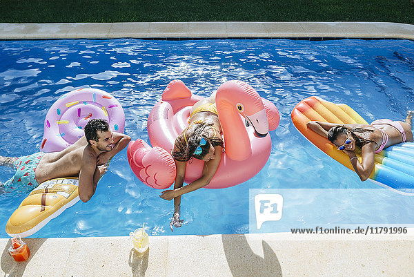 Happy friends on floats in swimming pool