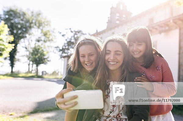 Drei glückliche Mädchen,  die mit einem Selfie nach draußen gehen.