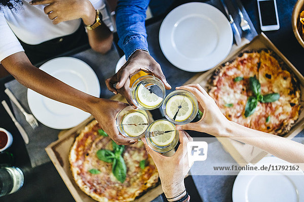 Gruppe von Freunden mit Pizza und klirrendem Wasser zu Hause