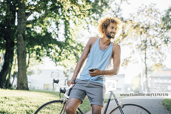 Man with beard and curly hair with bicycle in park