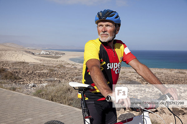 Spain  Canary Islands  Fuerteventura  senior man with mountainbike having a rest